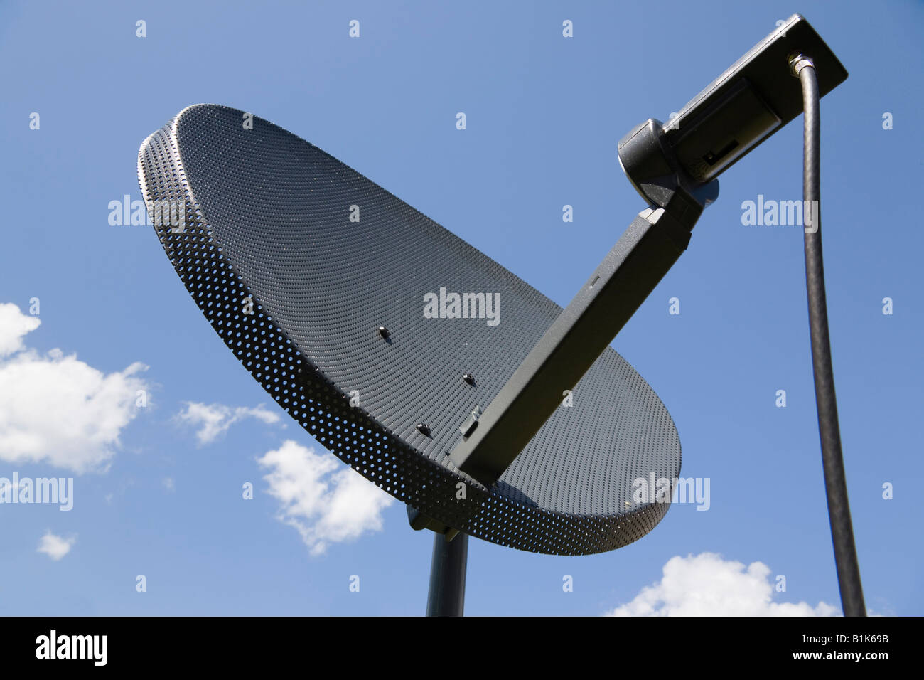 Britain UK Small domestic household satellite dish mounted on pole against blue sky in close up Stock Photo