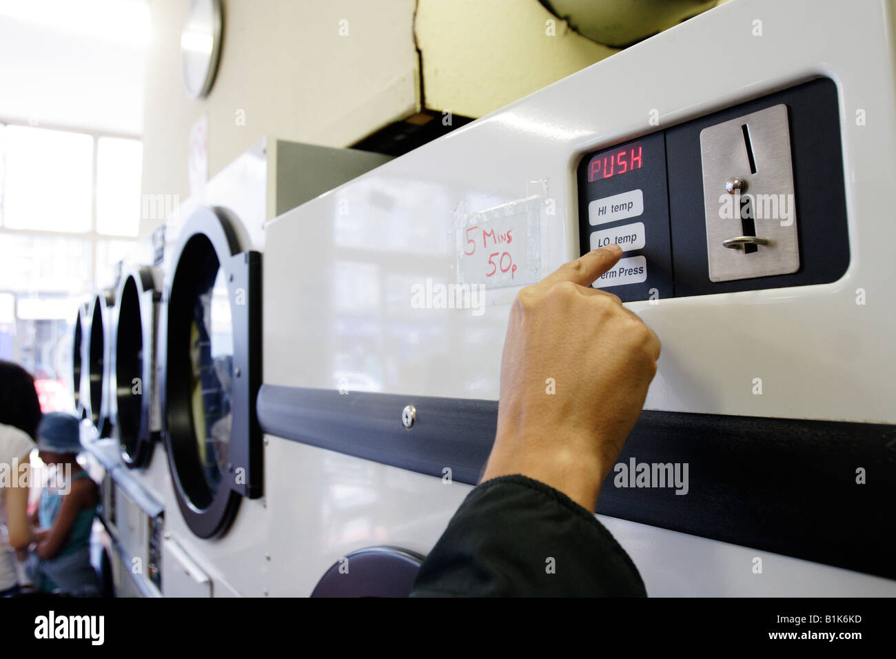 Inserting coins in a washing machine Stock Photo Alamy