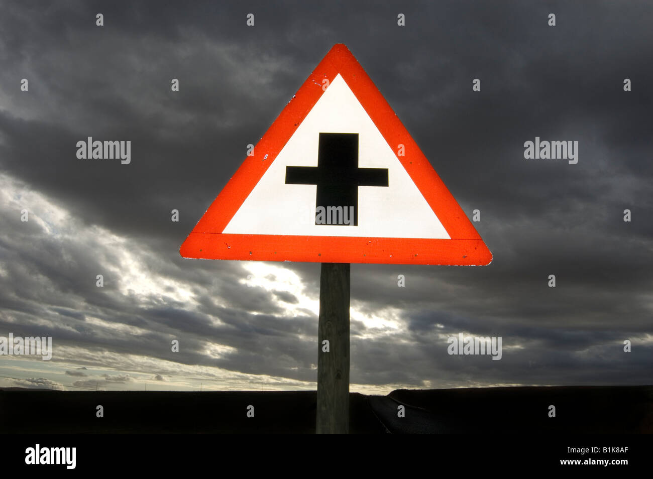 A sign warning of crossroads ahead at sunset Stock Photo