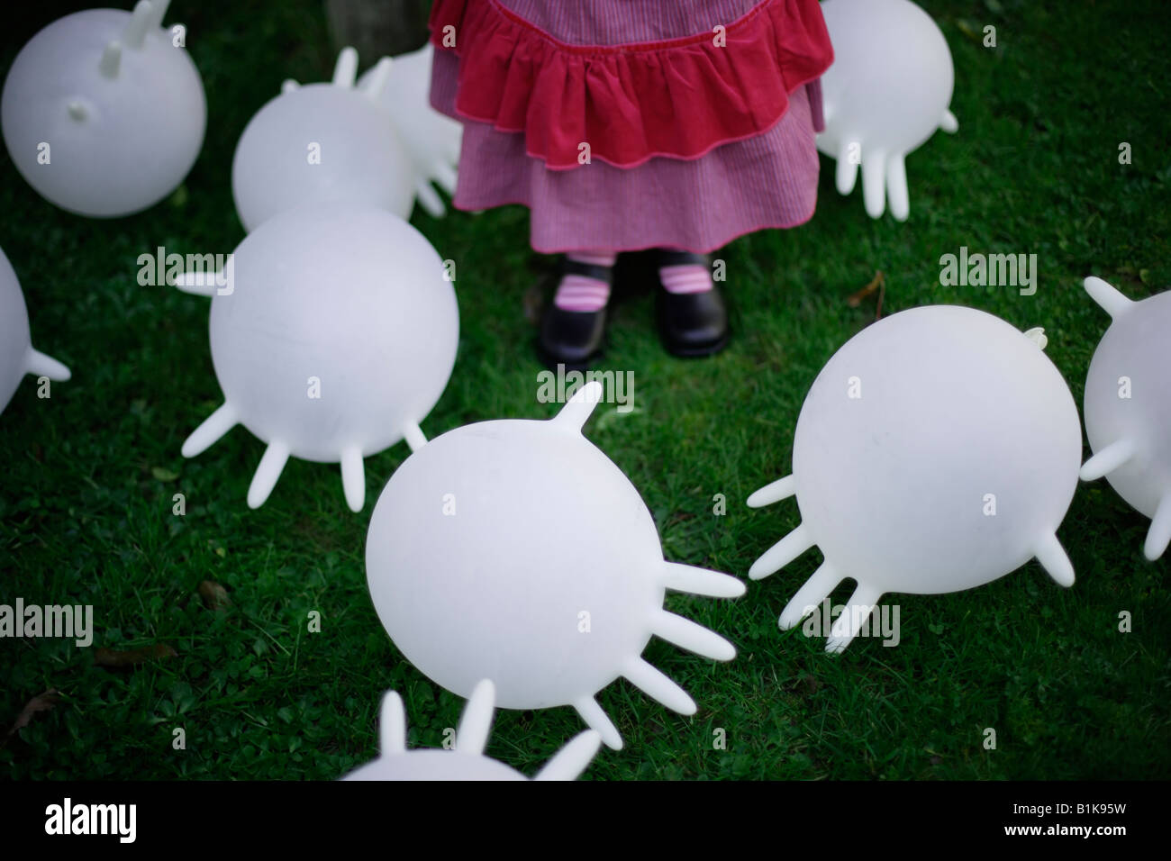 Inflated latex rubber gloves become makeshift balloons kicked around the garden by a four year old girl Stock Photo