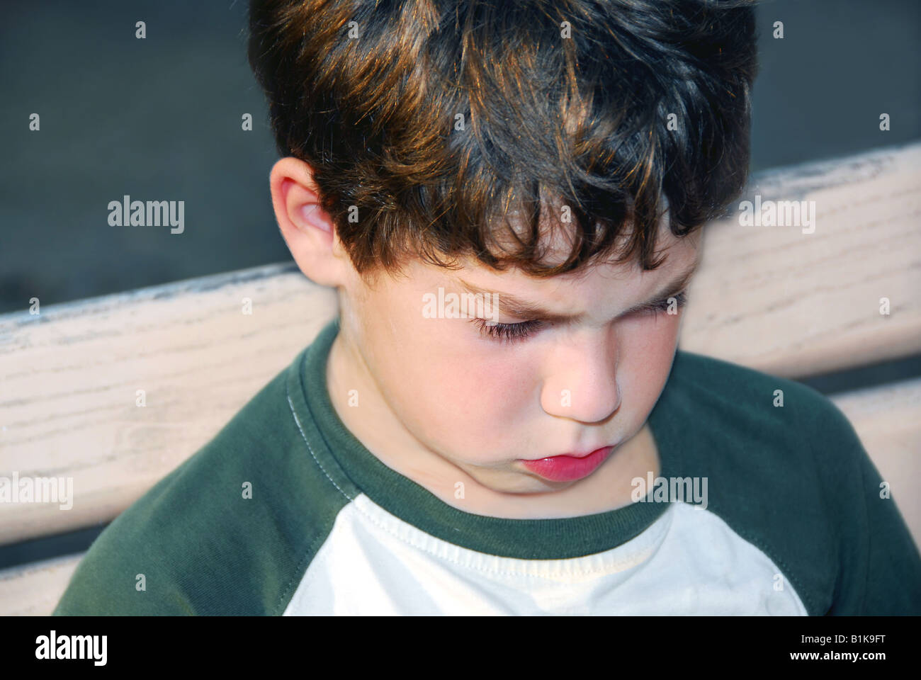 Portrait of a sad boy sitting on a bench in a park Stock Photo - Alamy