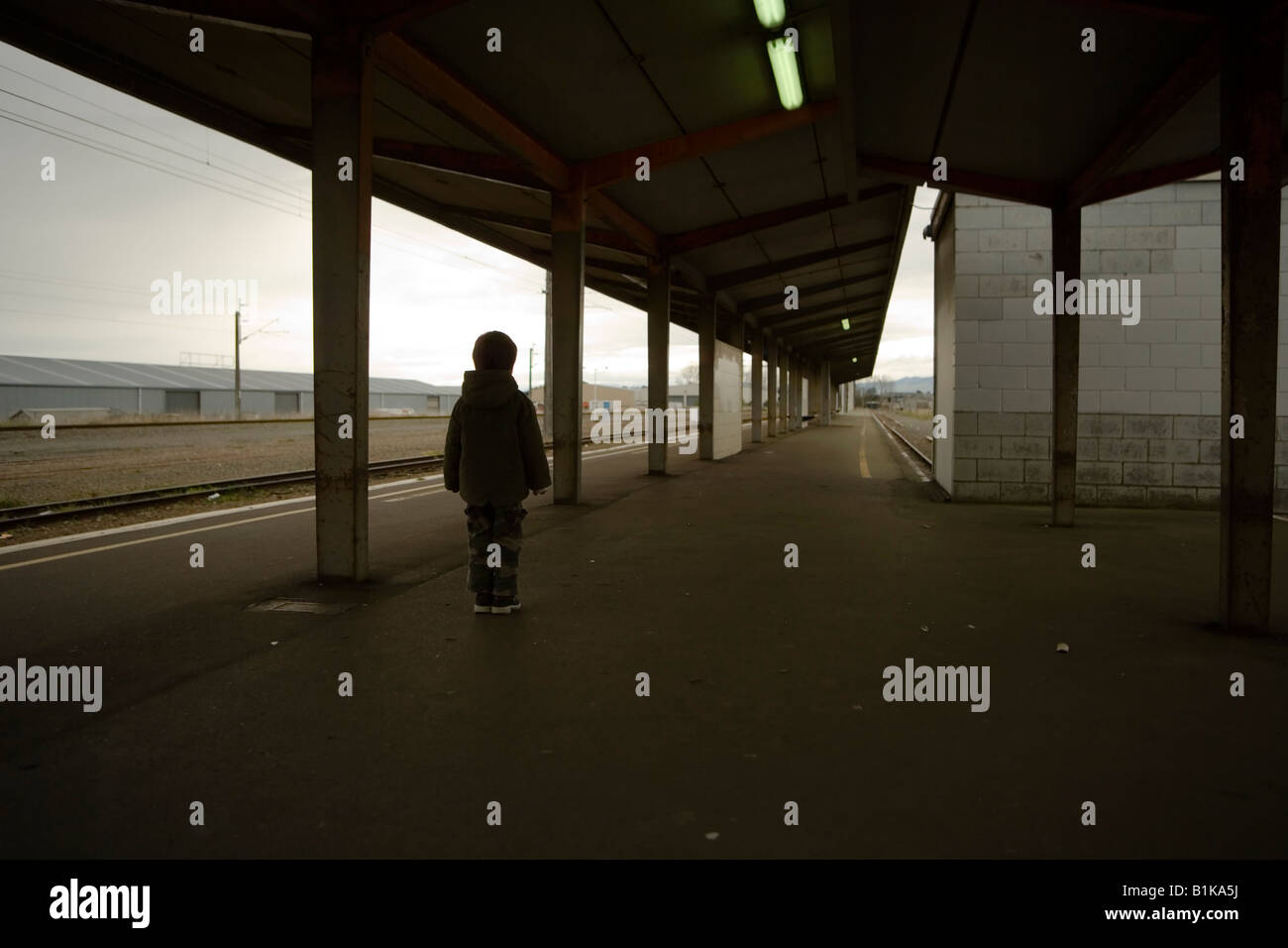 Boy aged six stands alone on railway station platform Palmerston North New Zealand Stock Photo