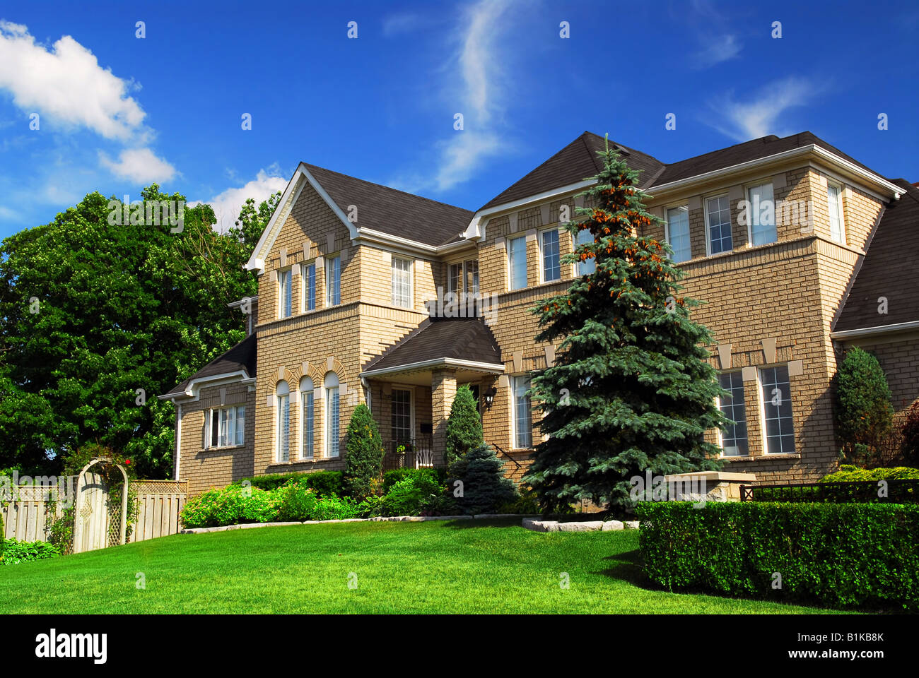Large upscale residential home with bright green lawn and blue sky Stock Photo