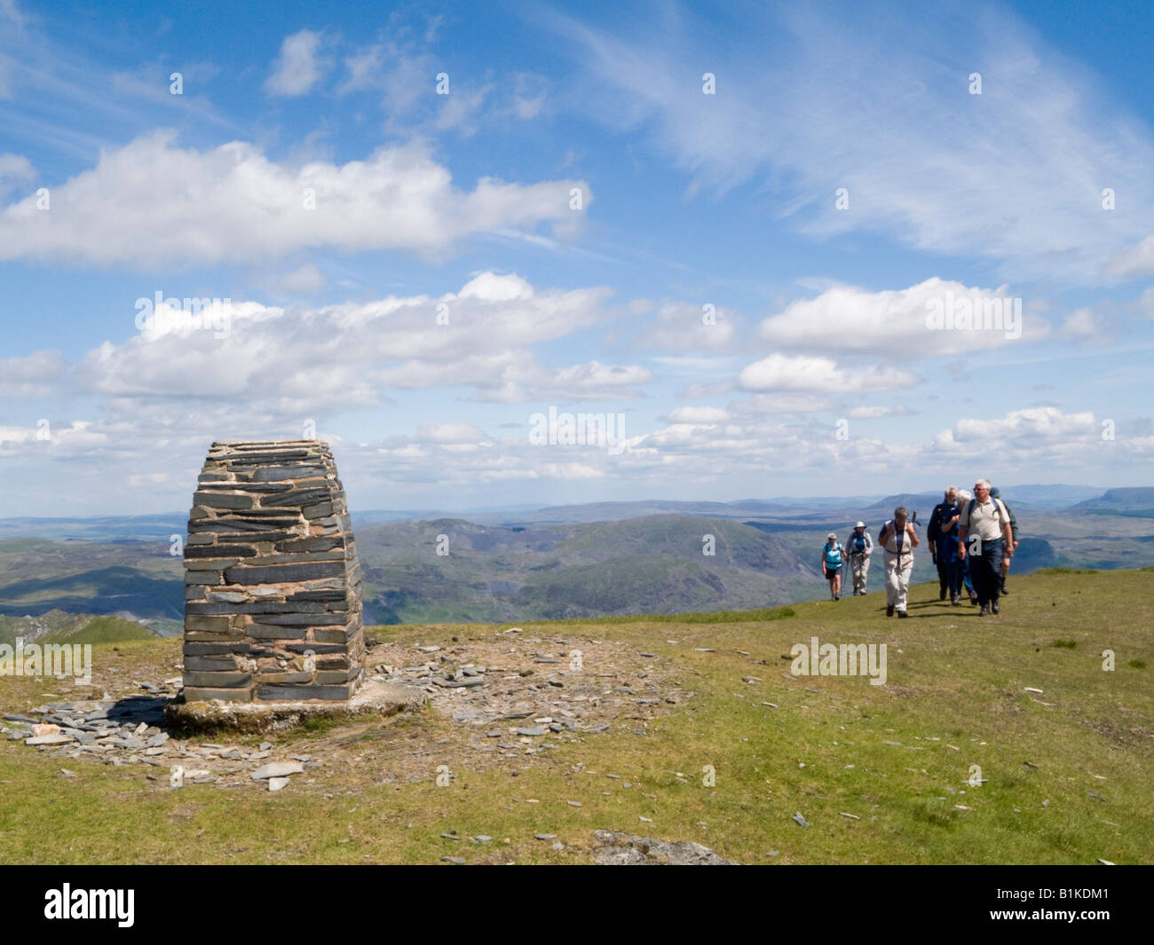 Group of people walking to summit cairn trig point on Moelwyn Mawr in Snowdonia National Park in summer North Wales UK Stock Photo