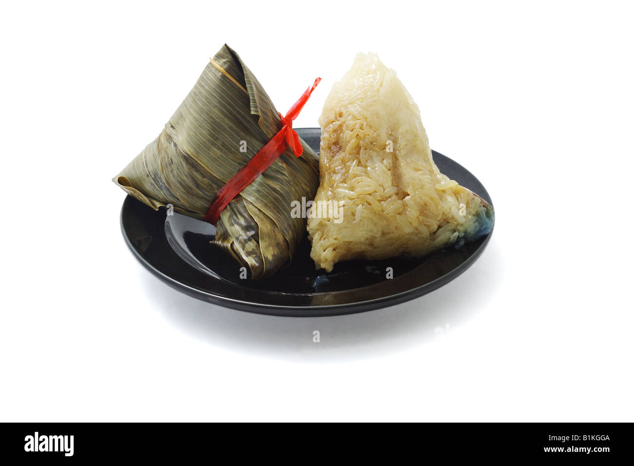 Wrapped and unwrapped Chinese rice dumplings on plate Stock Photo