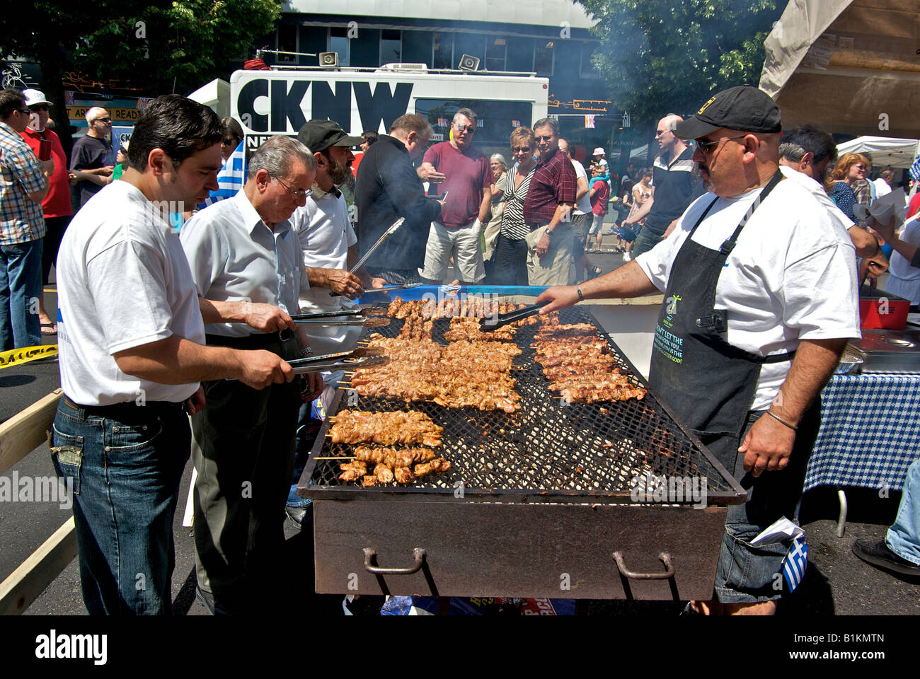 Volunteer cooks grill cooking lamb chicken pork and beef souvlaki on a