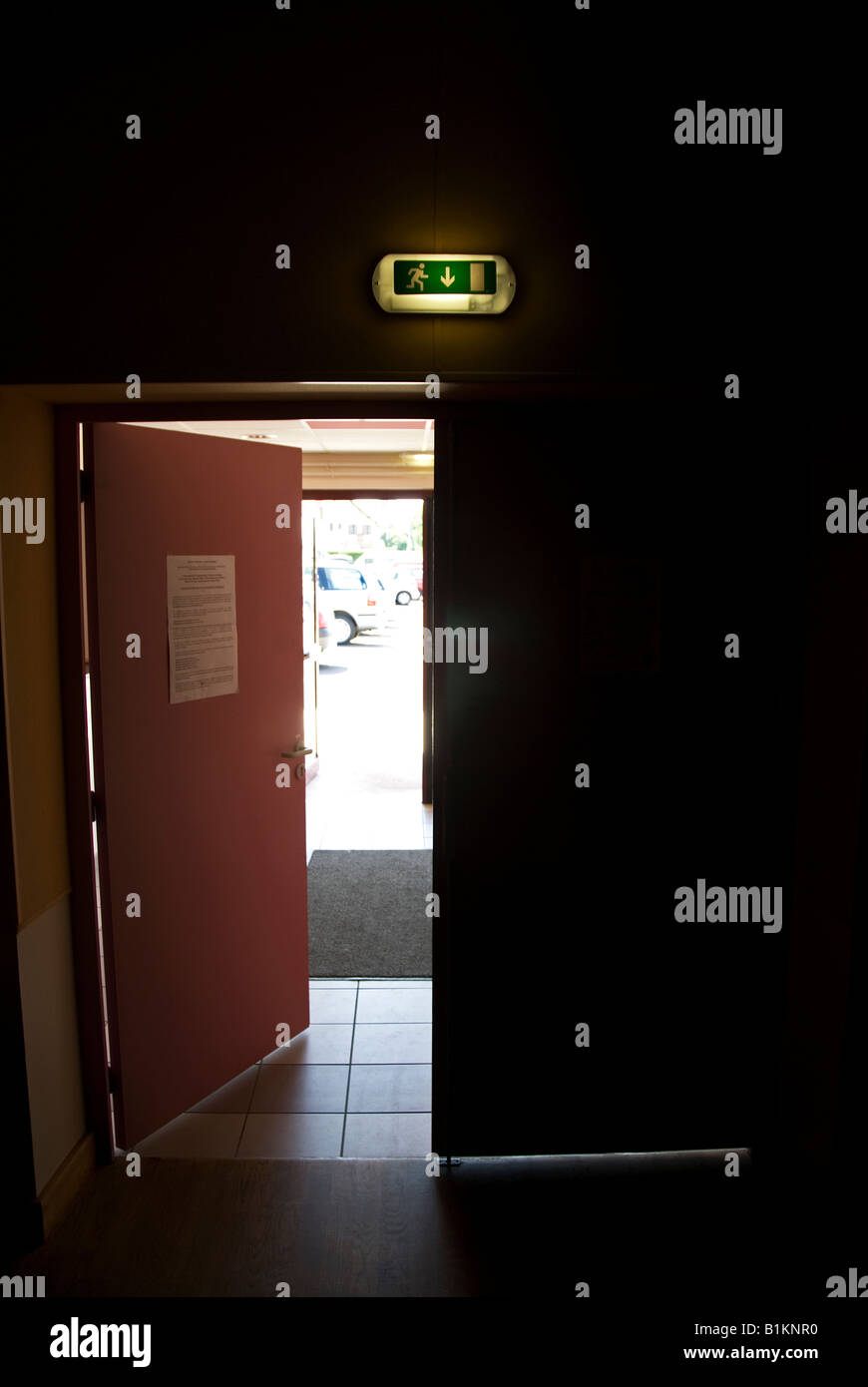 Stock photo of an illuminated exit sign above a door leading from a ...