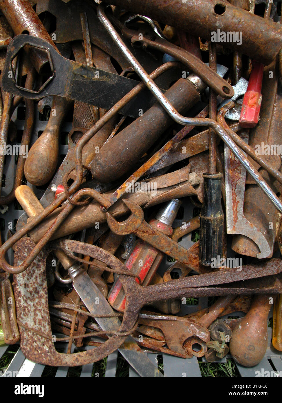 Box of rusty old tools for sale at boot fair. Including saws, knives, spanners, socket spanners and more. Stock Photo