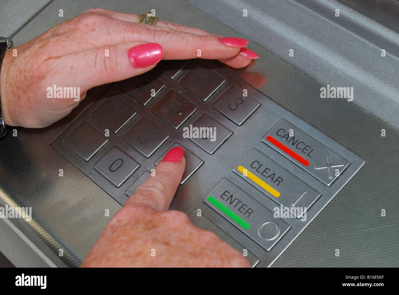 Woman guarding her security code with her hand on cash machine, Ascot, Berkshire, England, United Kingdom Stock Photo