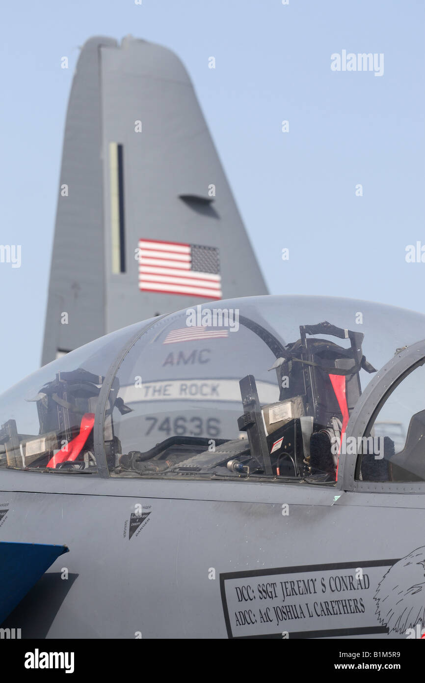 USAF military air power Boeing F-15E Strike Eagle cockpit canopy with Lockheed Martin C-130 Hercules tail behind Stock Photo