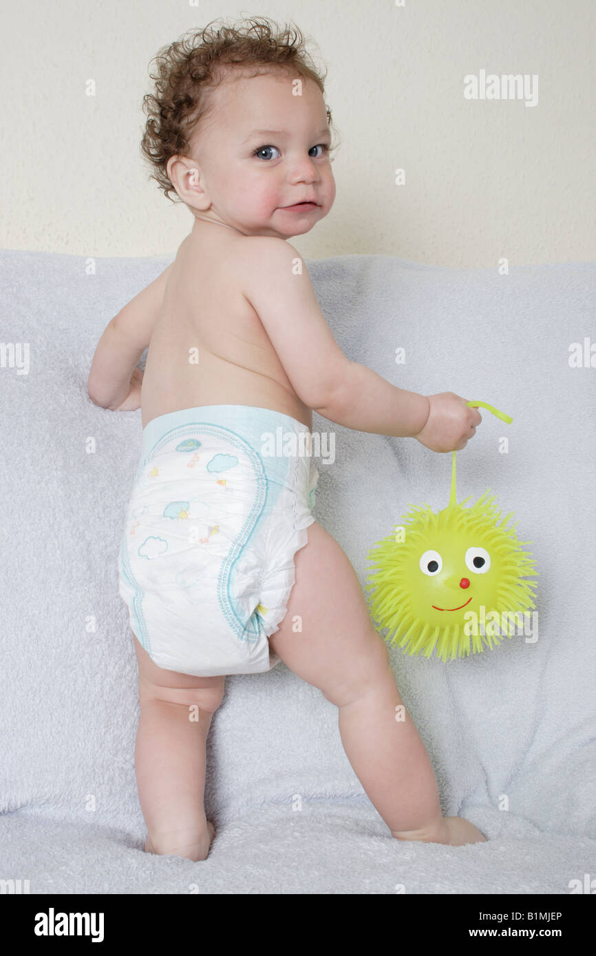 portrait little baby in nappy playing with yellow rubbery toy Stock