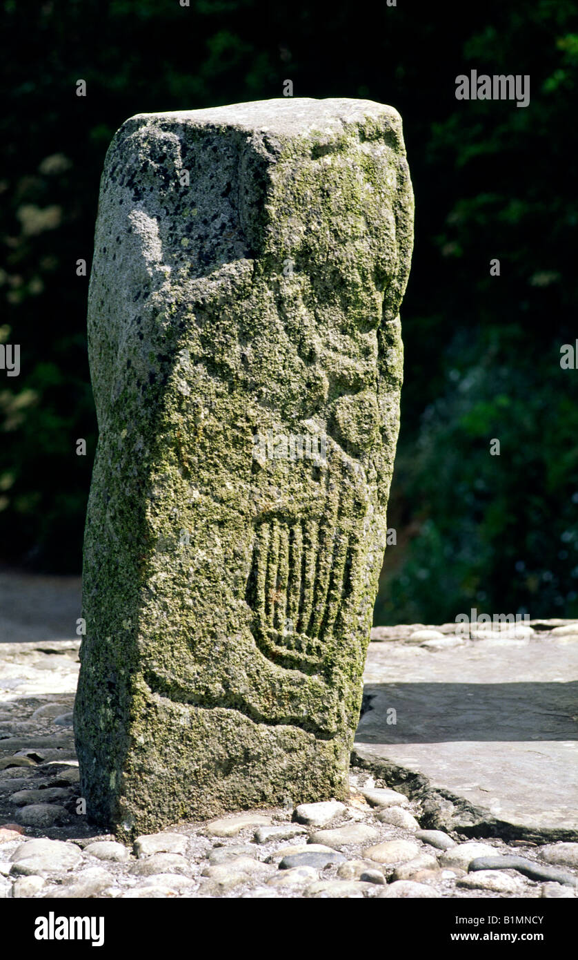 Man playing Celtic clarsach harp on one of 2 carved stones flanking the