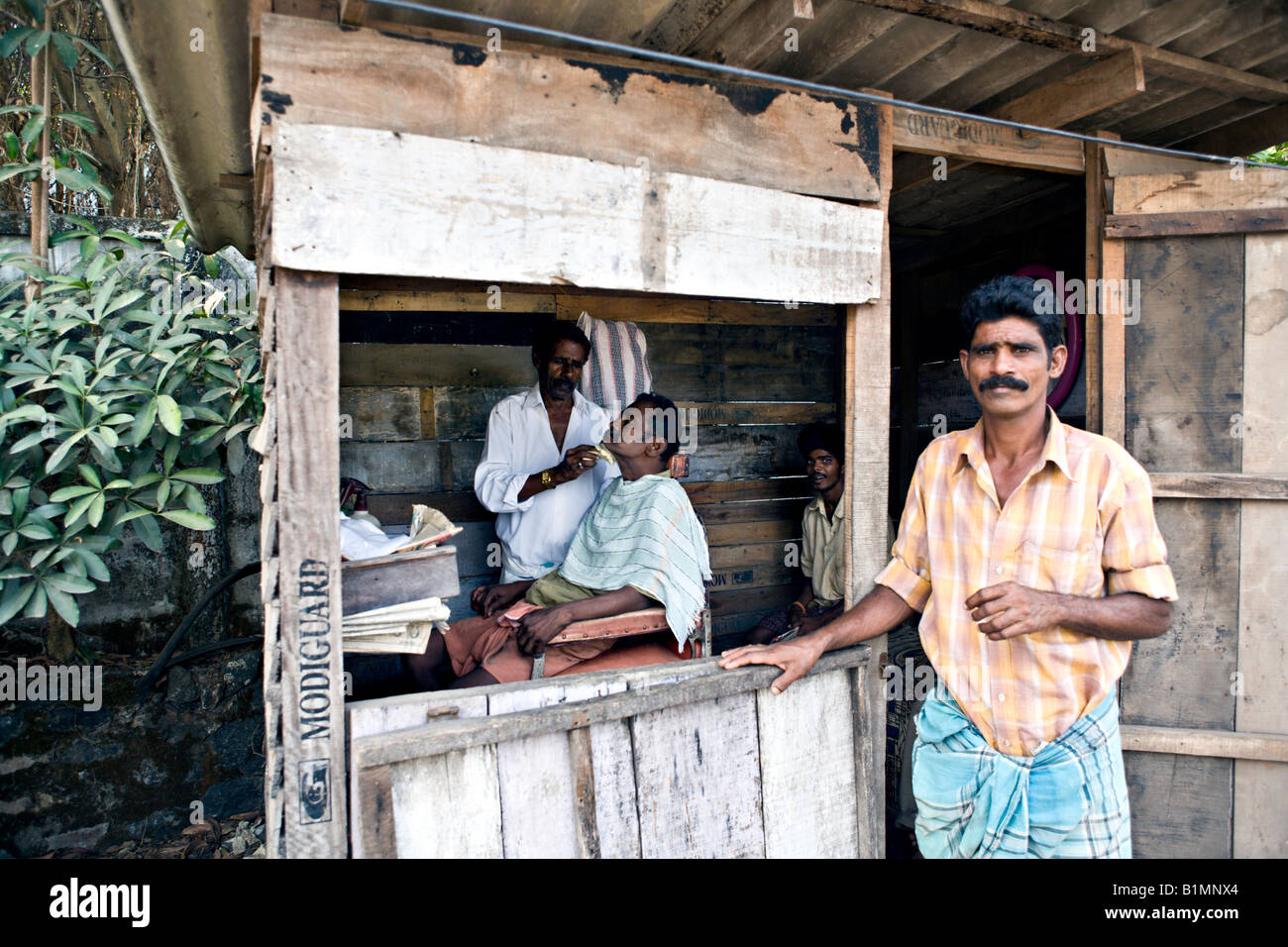 INDIA KERALA KOCHI Tiny barber shop in a shack on a dirt street in the