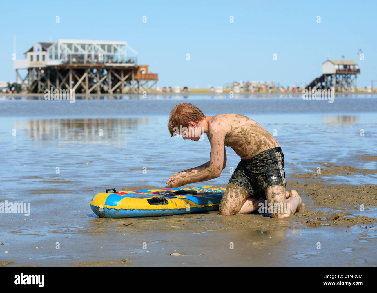 young boy covered in mud playing at a beach Stock Photo