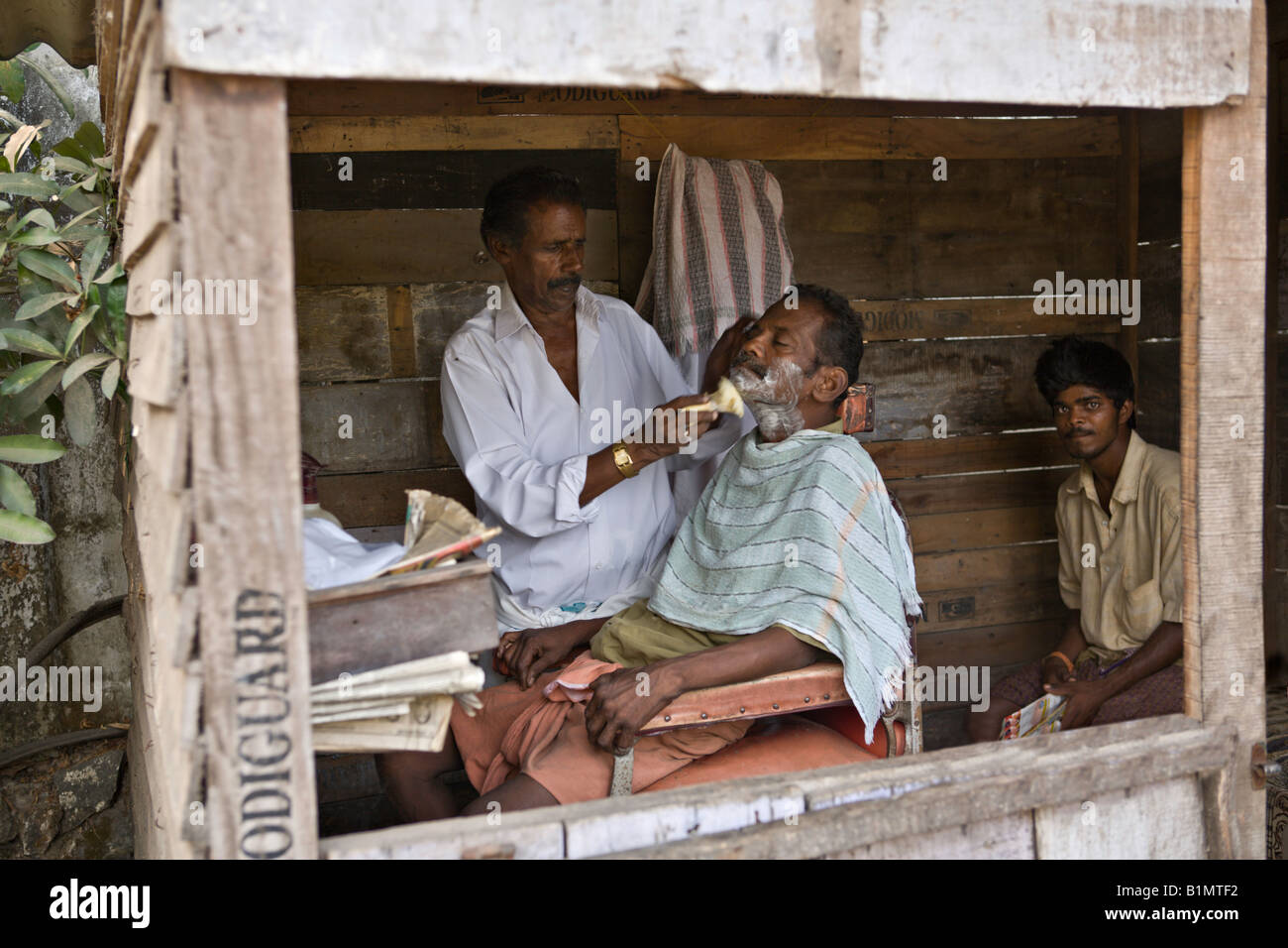 INDIA KERALA KOCHI Tiny barber shop in a shack on a dirt street in the
