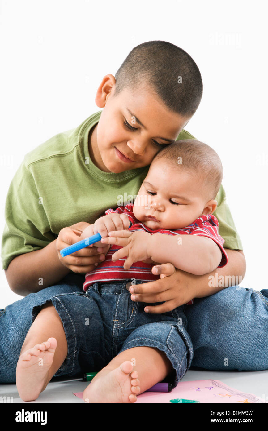 Young latino boy holding baby brother on lap Stock Photo Alamy
