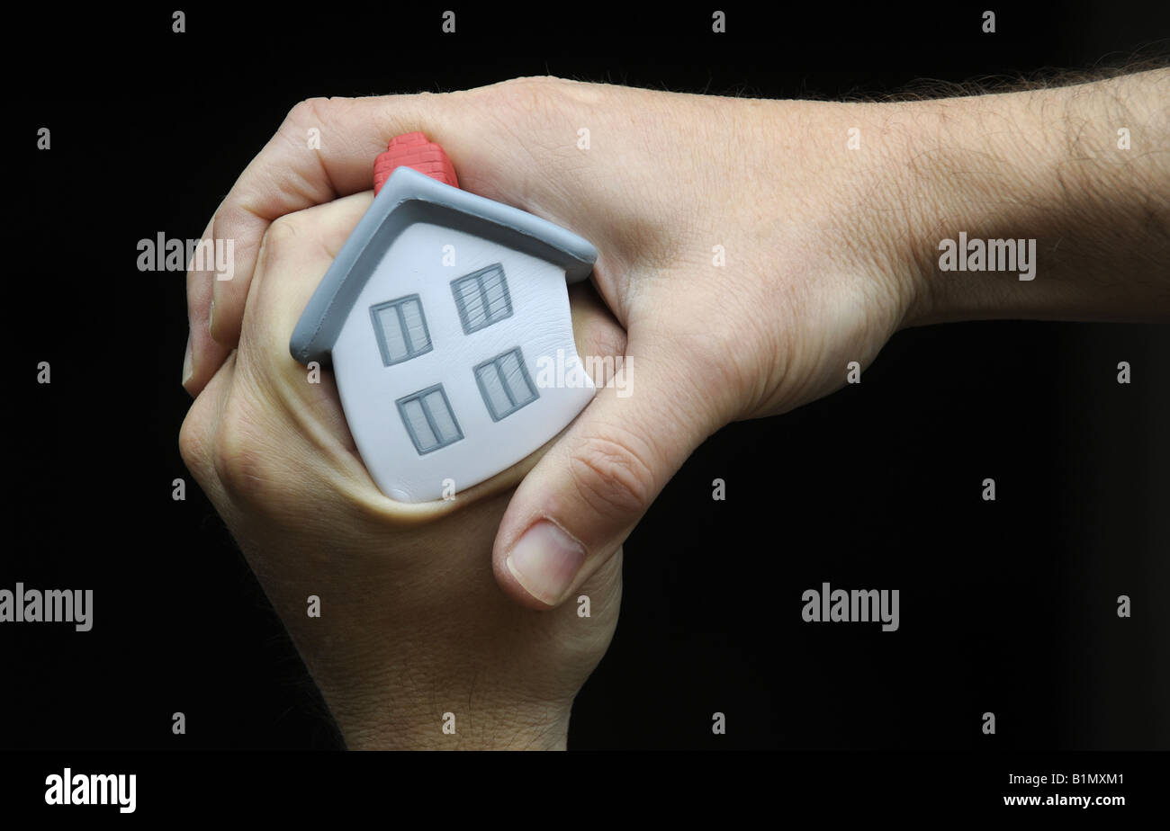 MODEL HOUSE SQUEEZED AND HELD IN A MANS HAND RE HOUSE PRICES PROPERTY MARKET ECONOMY HOME BUYERS ETC,UK. Stock Photo