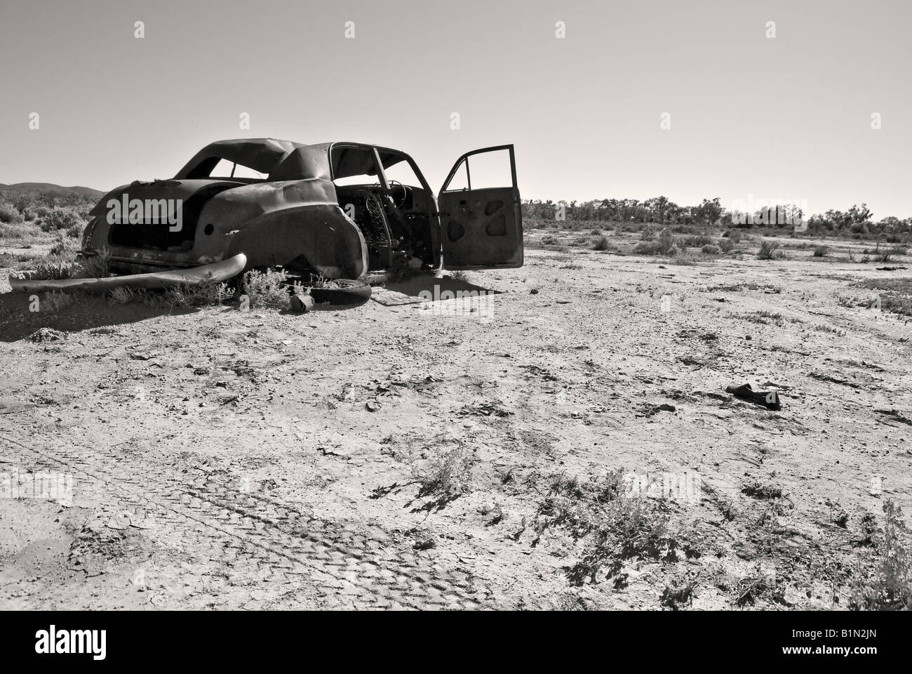 black and white image of an old rusty car in the desert Stock Photo