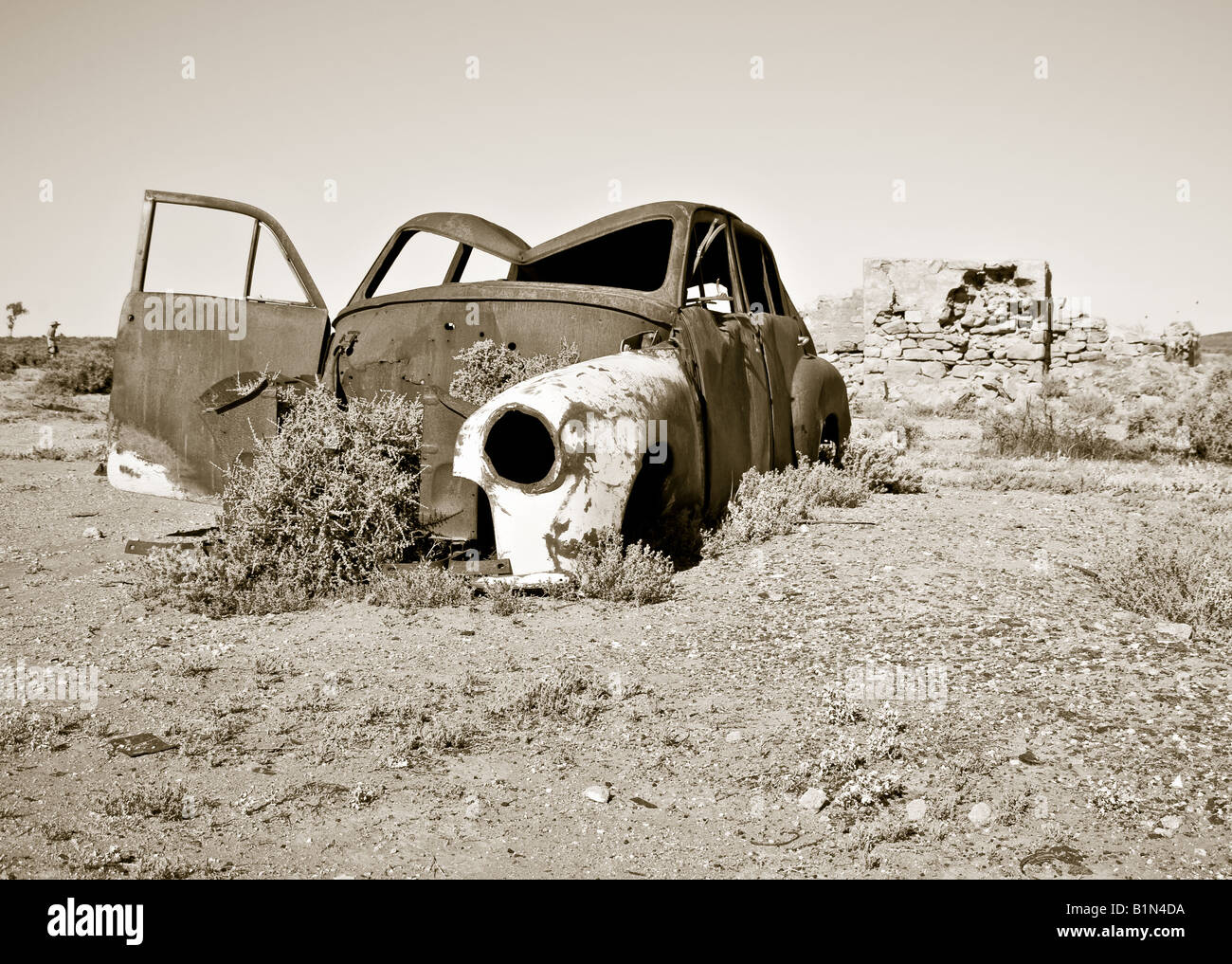 black and white image of an old rusty car in the desert Stock Photo