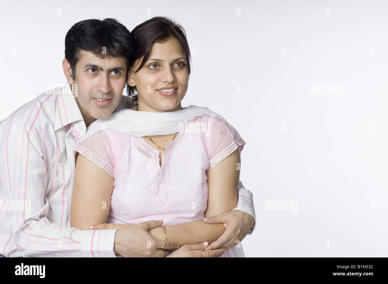 Close-up of a mid adult man hugging a mid adult woman from behind Stock ...
