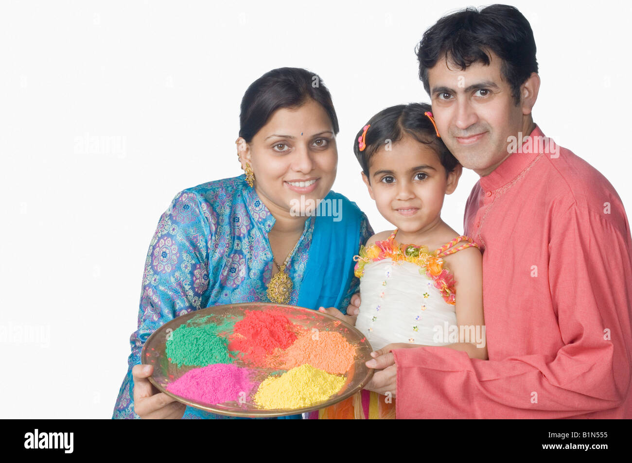 Portrait of a mid adult couple with their daughter holding a plate of powder paint and smiling Stock Photo
