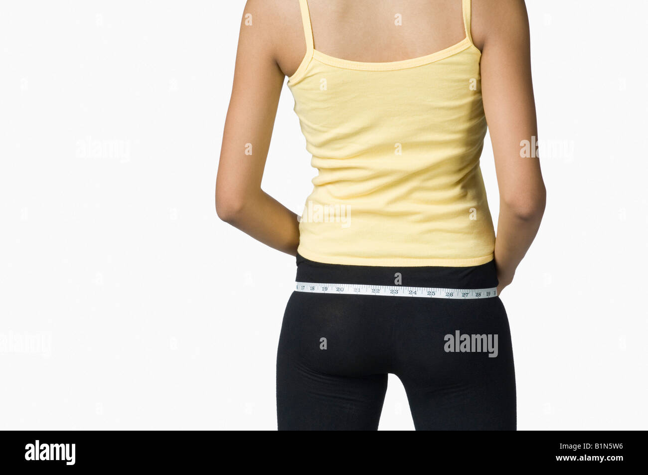 Rear view of a young woman measuring her hip with a tape measure Stock Photo