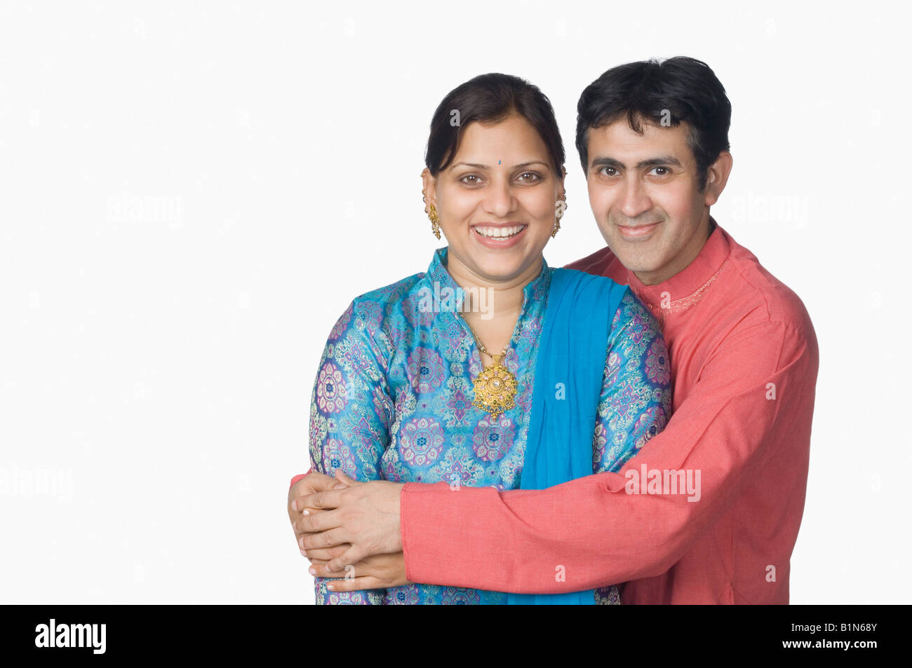Portrait of a mid adult man embracing a mid adult woman from behind ...