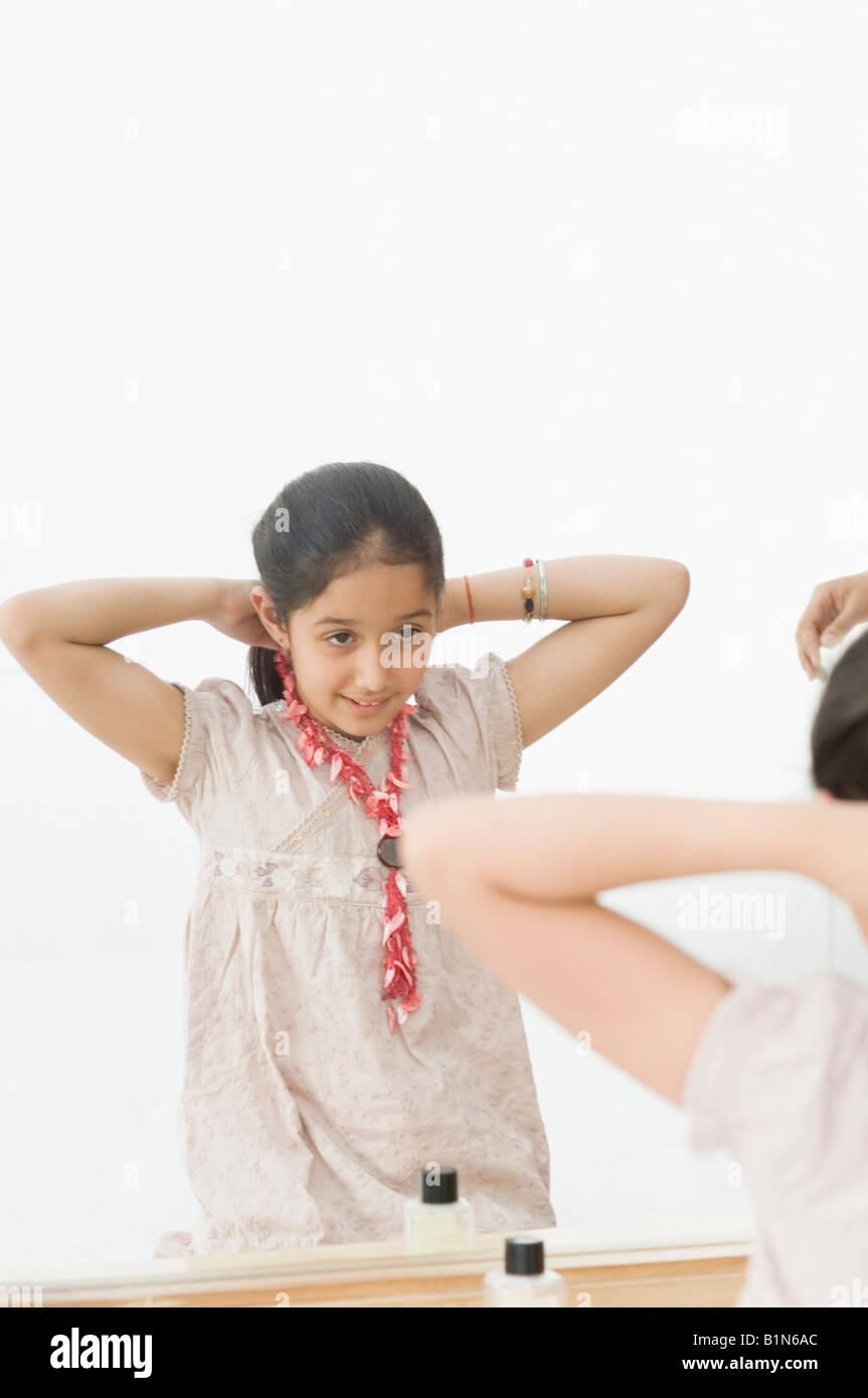 Girl adjusting her hair in front of a mirror Stock Photo - Alamy