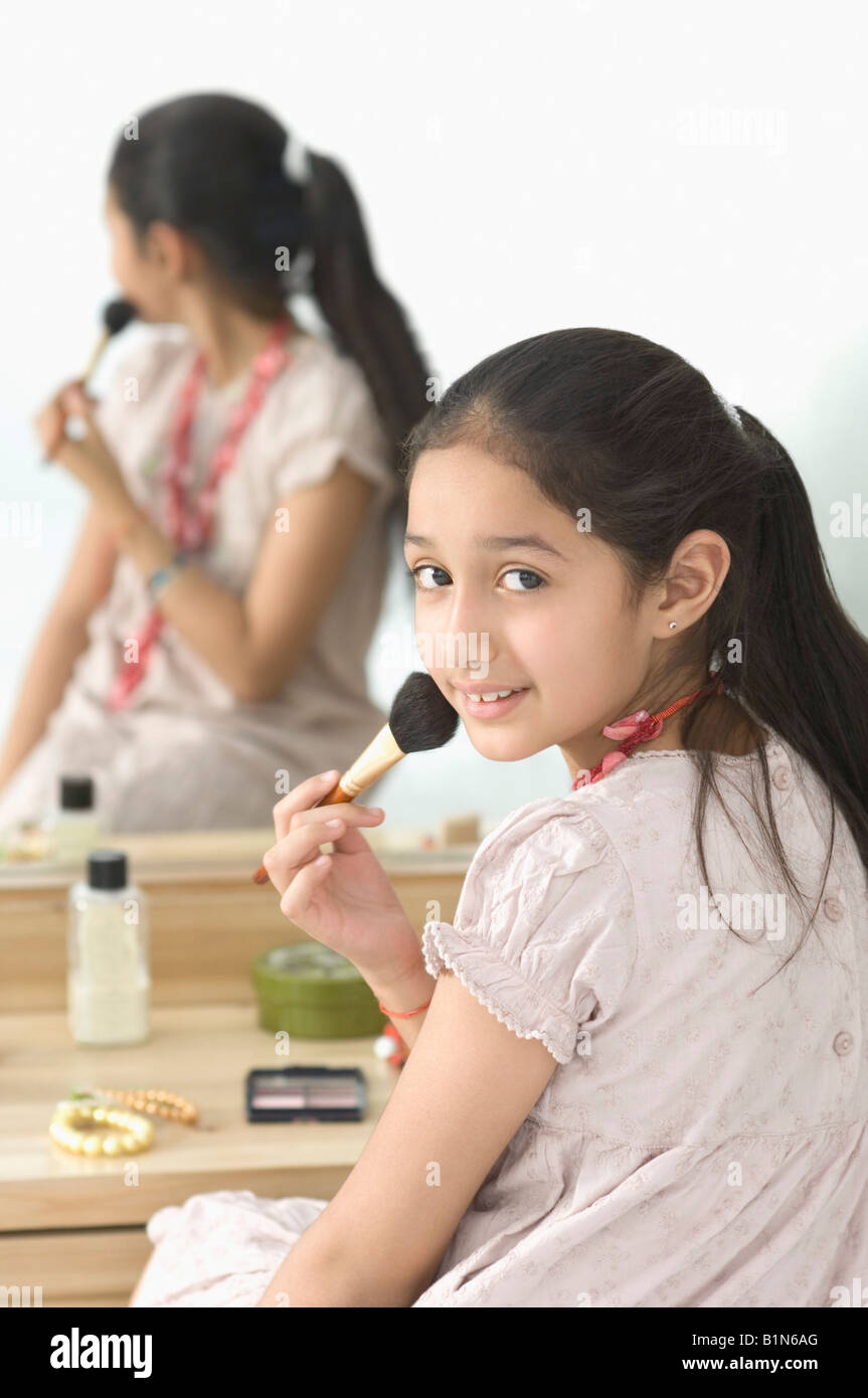 Reflection of a girl applying makeup in dressing table mirror Stock