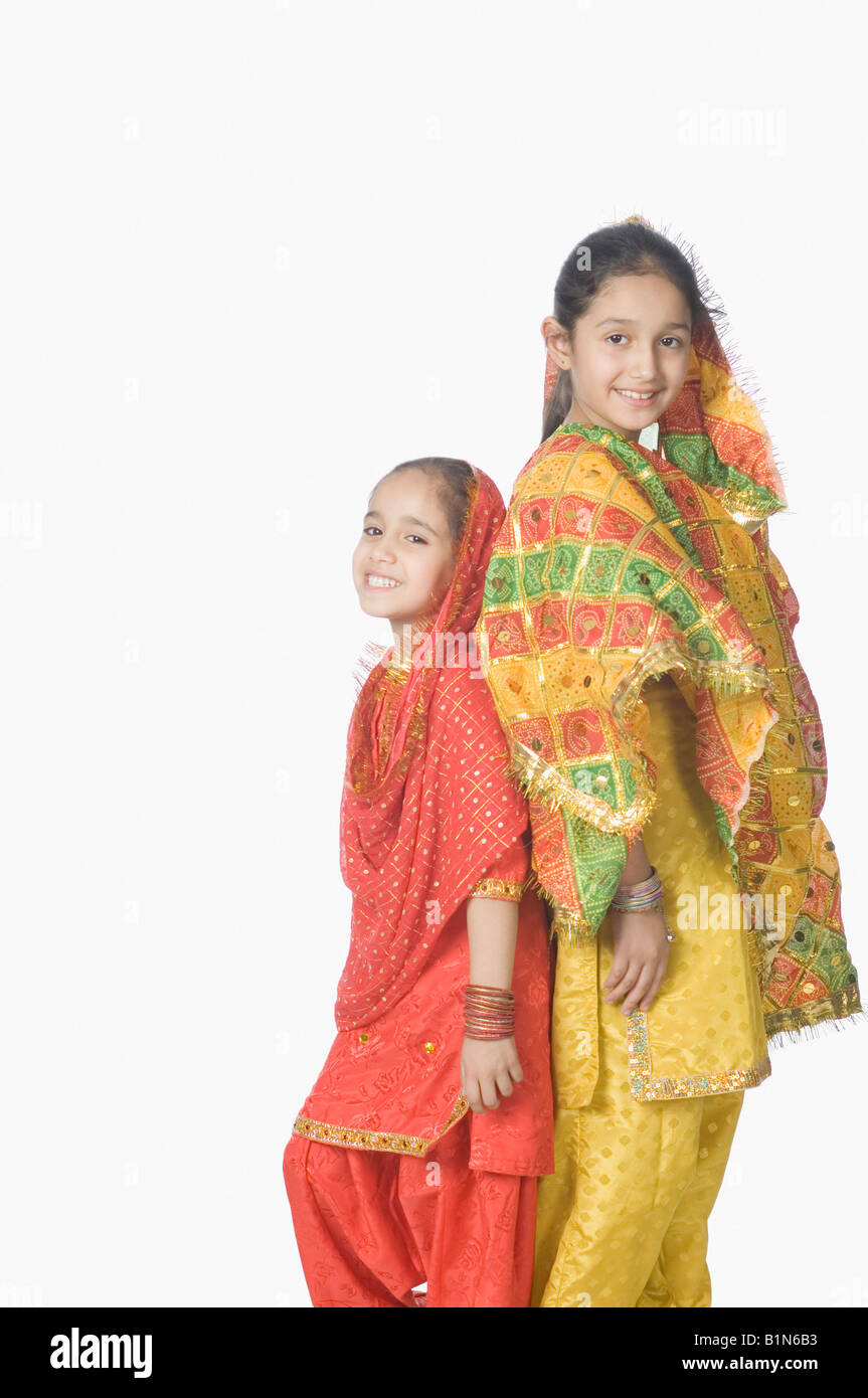 Portrait of two girls standing back to back and smiling Stock Photo - Alamy