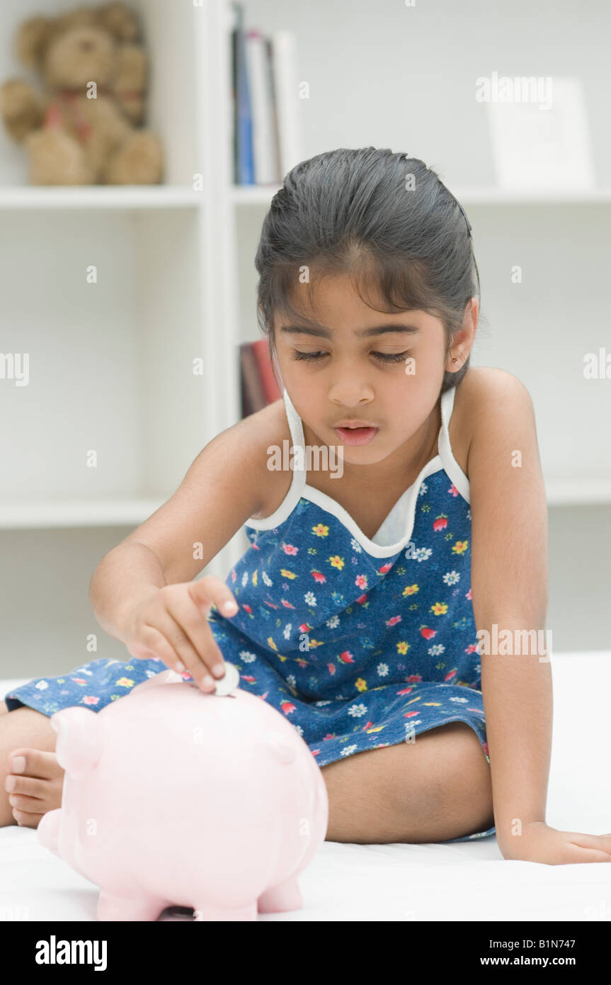 Girl putting a coin into a piggy bank Stock Photo - Alamy
