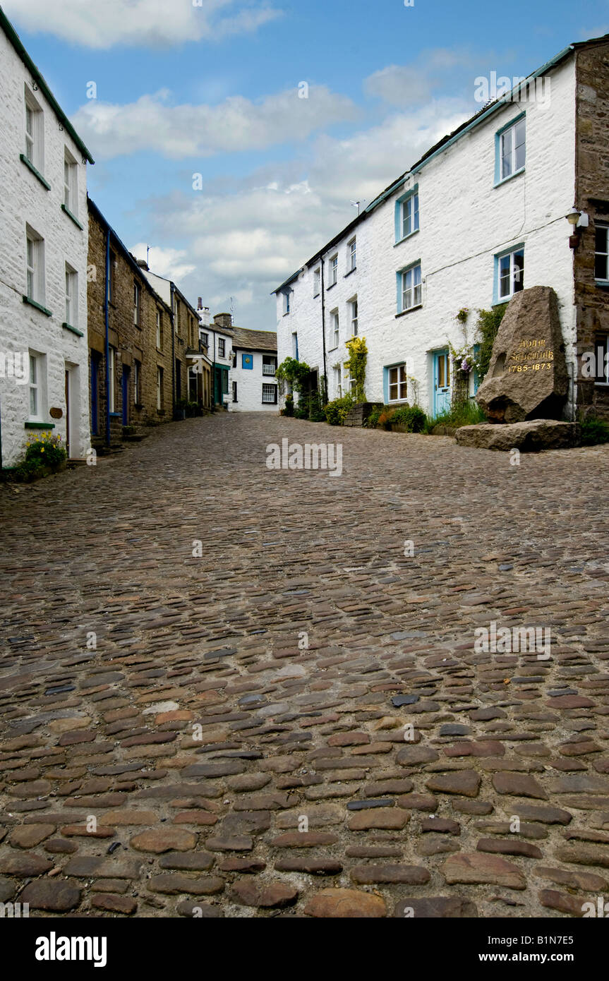 Looking up cobbled main street towards the Sedgewick Stone and the Sun Inn in Dent Yorkshire Dales National park near Sedbergh Stock Photo