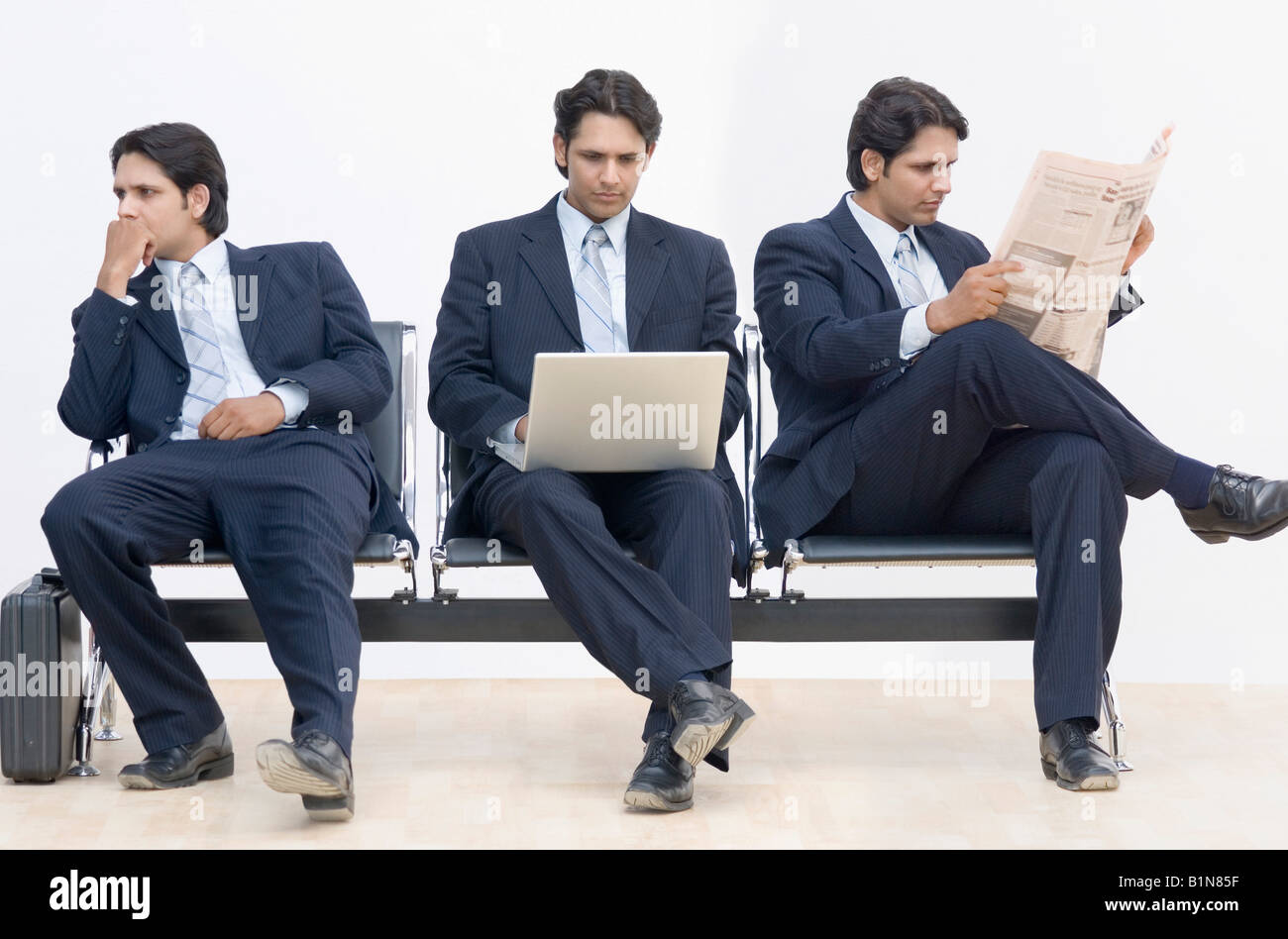 Three businessmen sitting on a bench Stock Photo - Alamy