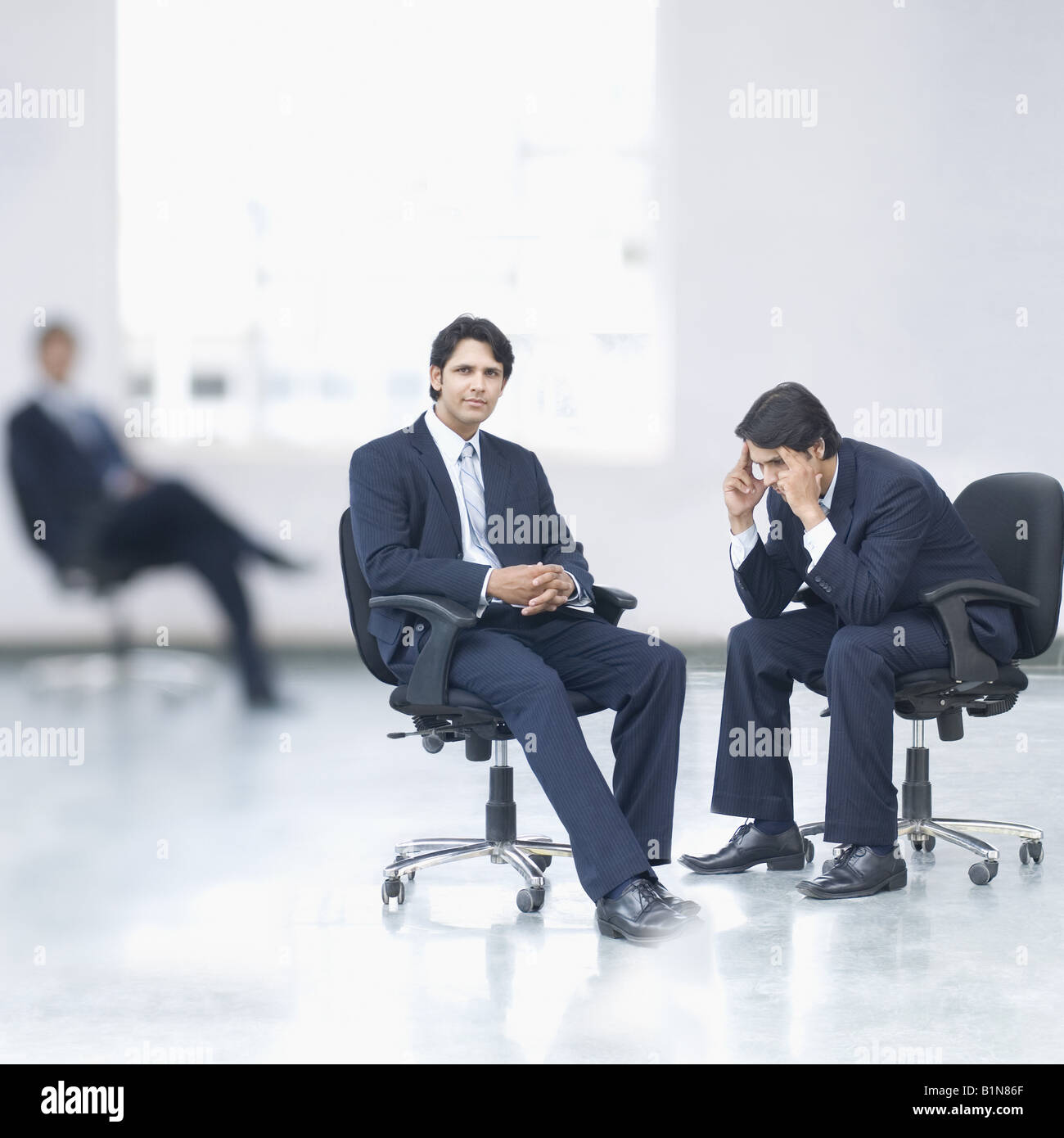 Three businessmen sitting in an office Stock Photo - Alamy