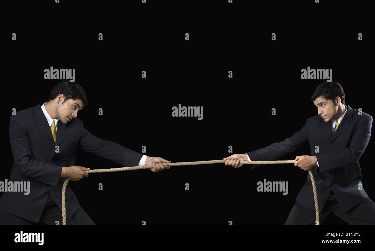 Businessman and his clone playing tug-of-war Stock Photo