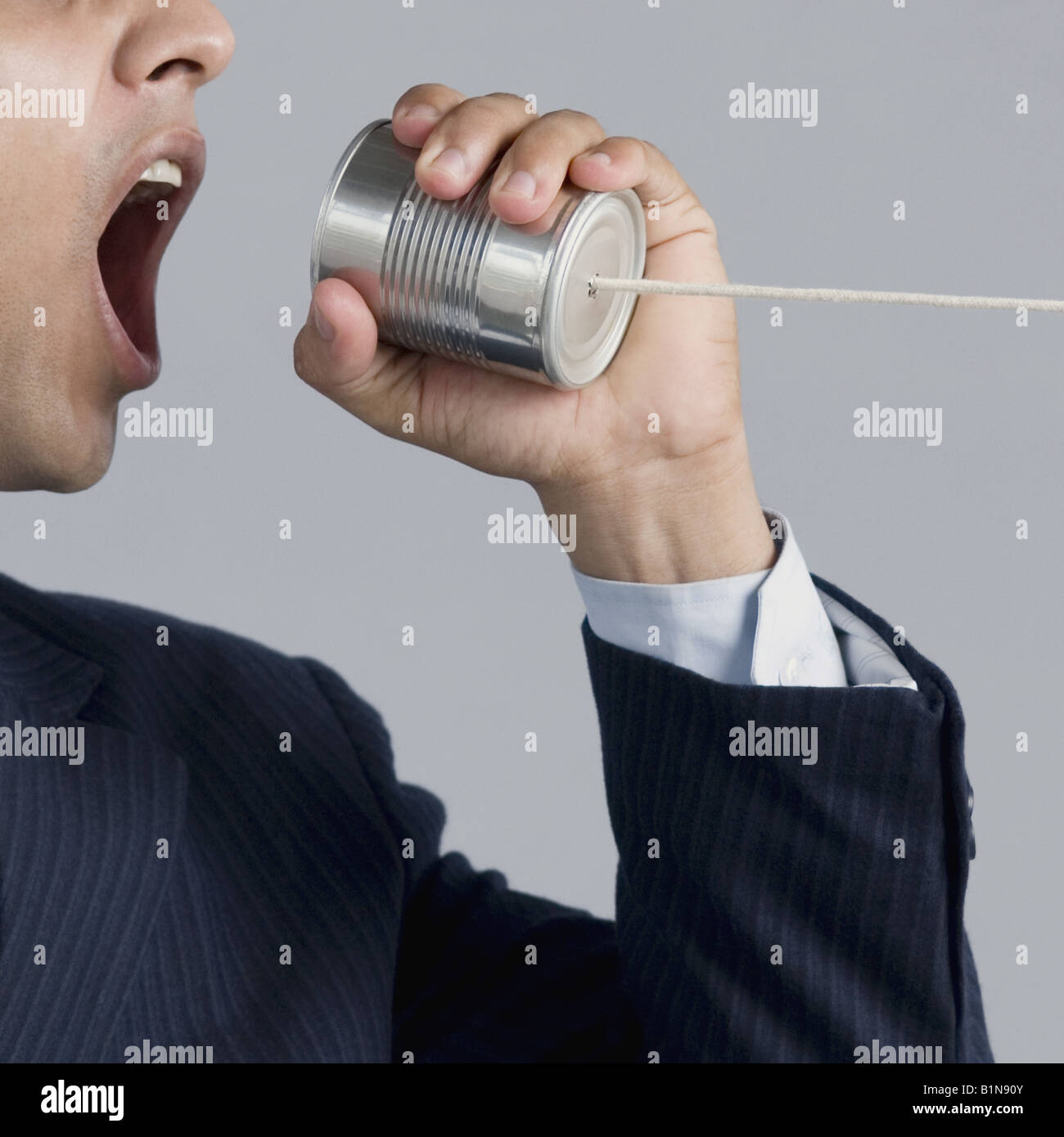 Businessman shouting into a tin can phone Stock Photo