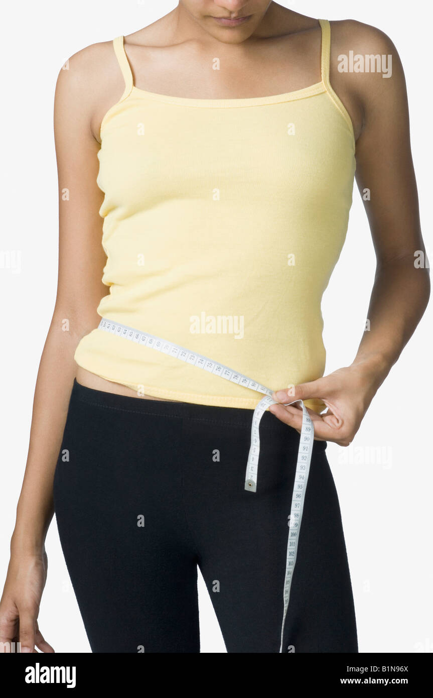 Young woman measuring her waist with a tape measure Stock Photo