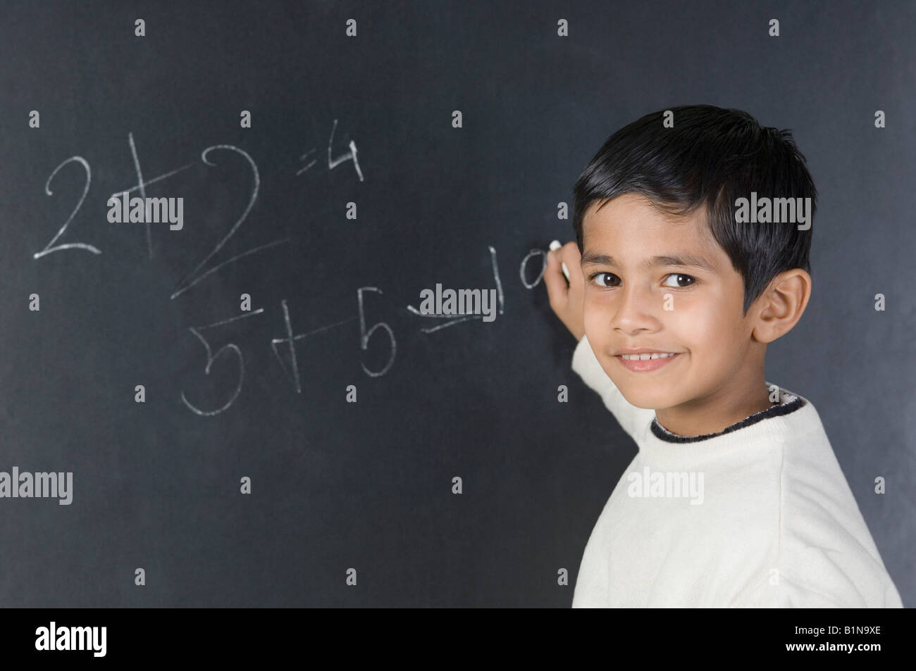 Portrait of a boy solving mathematical symbols on a blackboard Stock ...