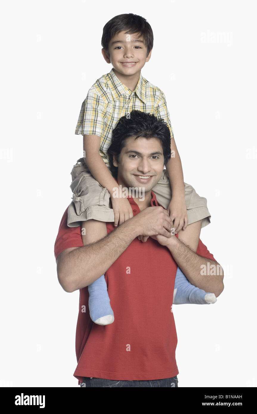 Portrait of a young man carrying his son on his shoulders Stock Photo ...