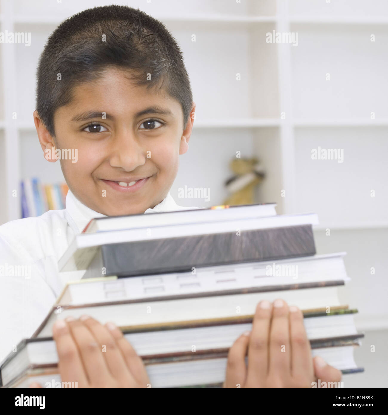 Portrait of a boy holding a stack of books and smiling Stock Photo - Alamy