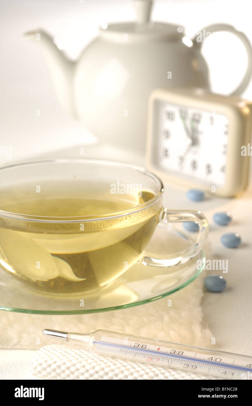 Tea with clinical thermometer, alarm clock, pills and teapot Stock