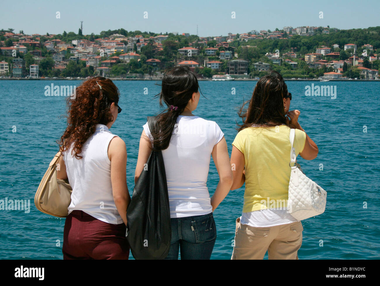 3 Turkish girls standing in front of the Bosphorus waiting for the ferry Stock Photo