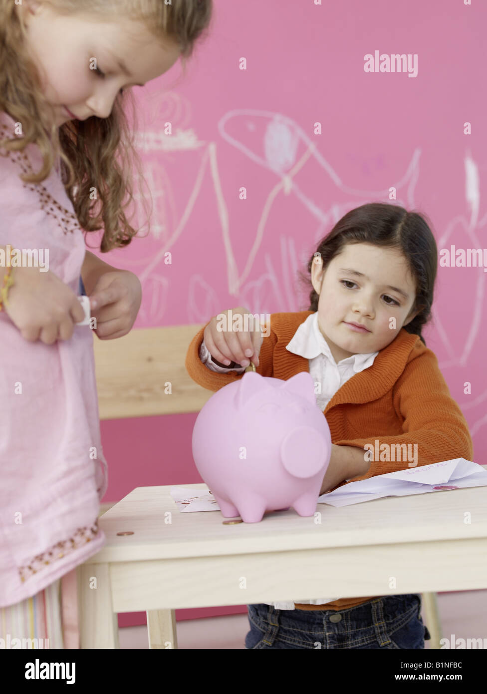 Girl is putting money in a piggy bank Stock Photo - Alamy