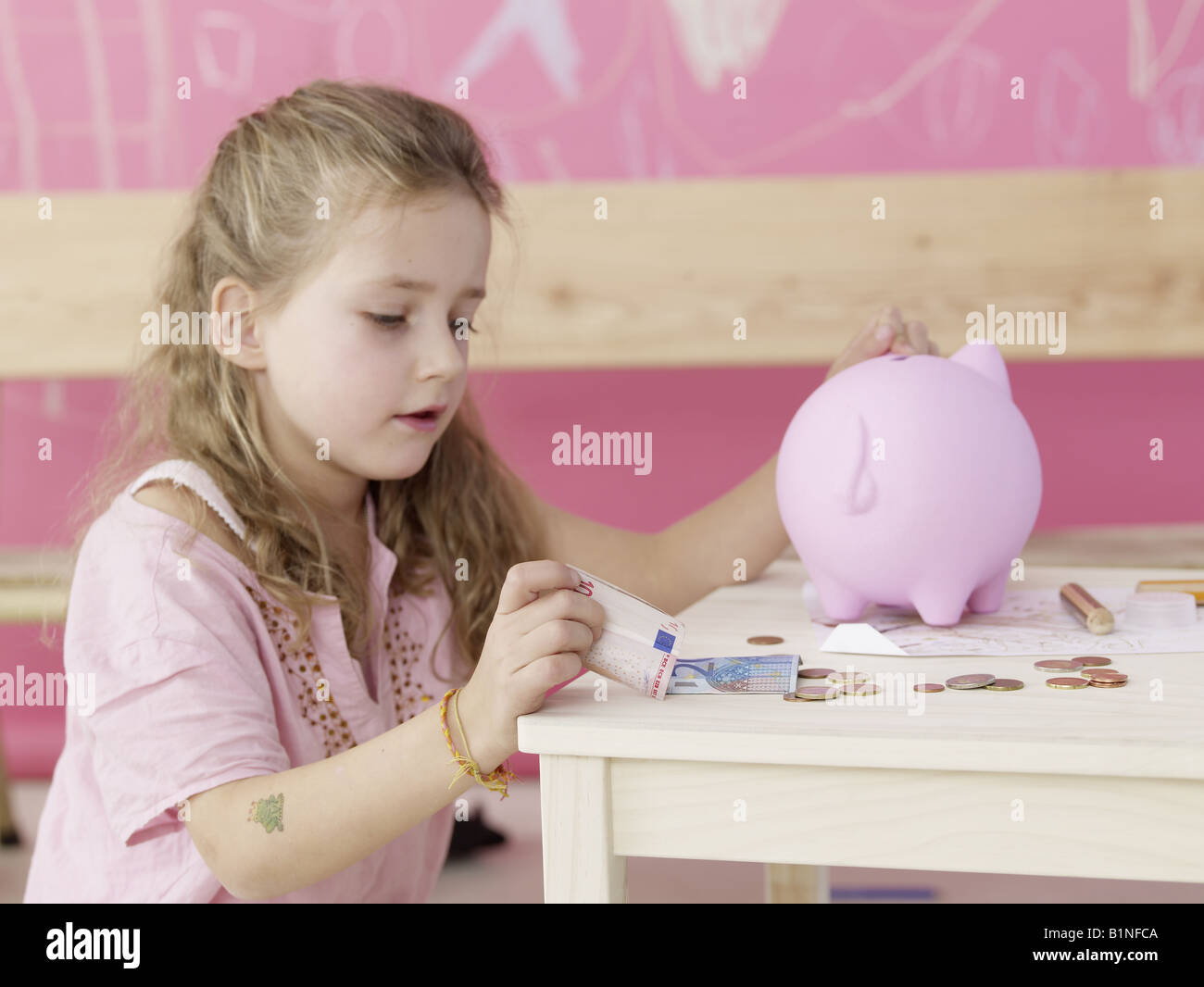 Girl is putting money in a piggy bank Stock Photo - Alamy