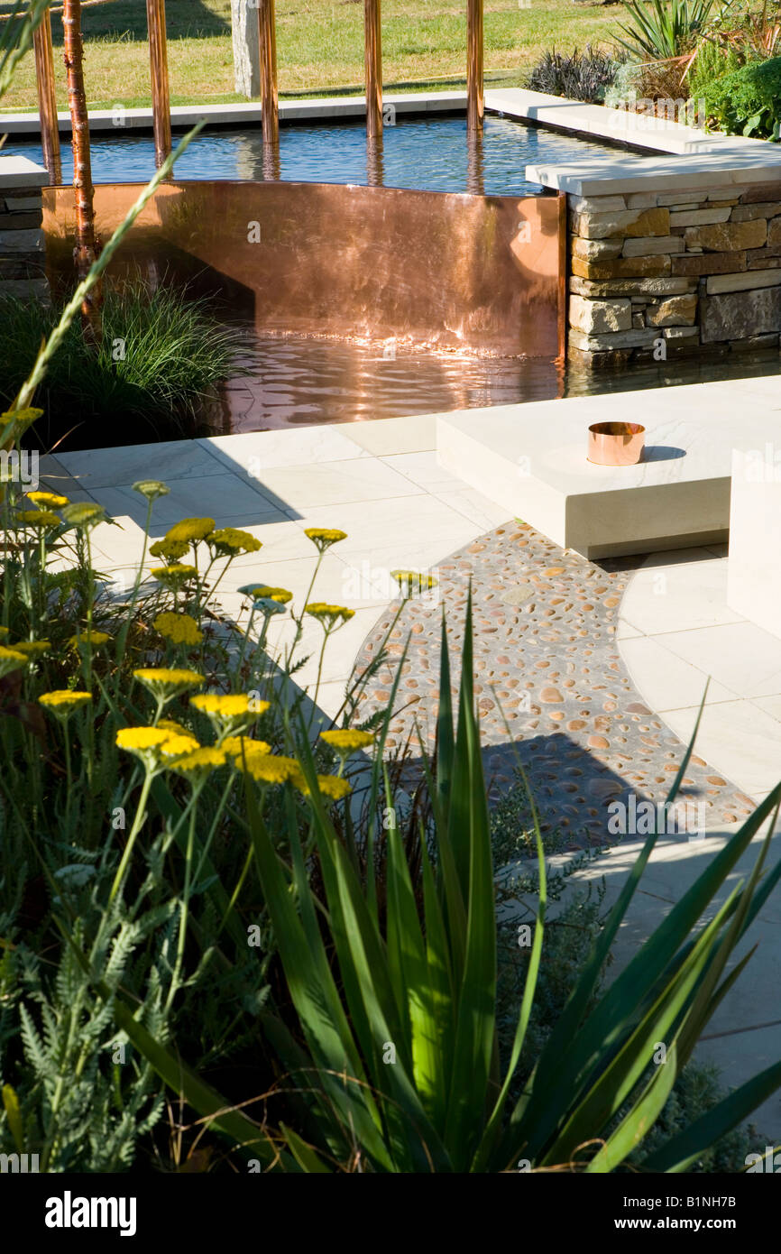 copper water feature with curving gravel path Stock Photo