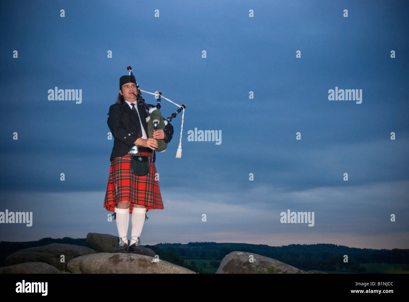 A lone bagpiper silhouetted against a late evening sky Stock Photo