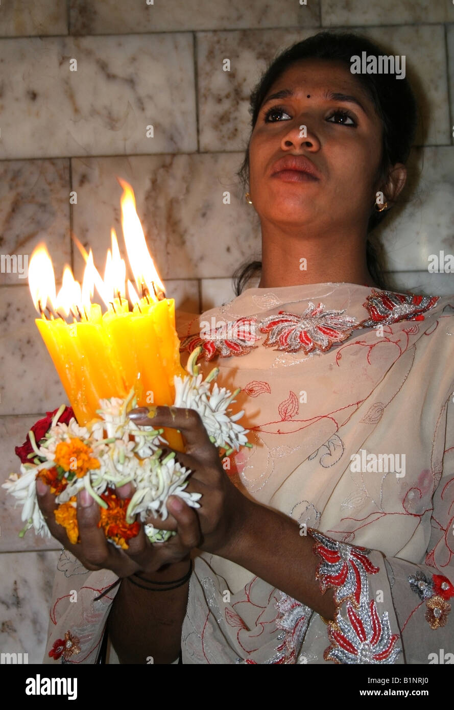 Catholic woman holds candles whilst praying to the Infant Jesus, Infant