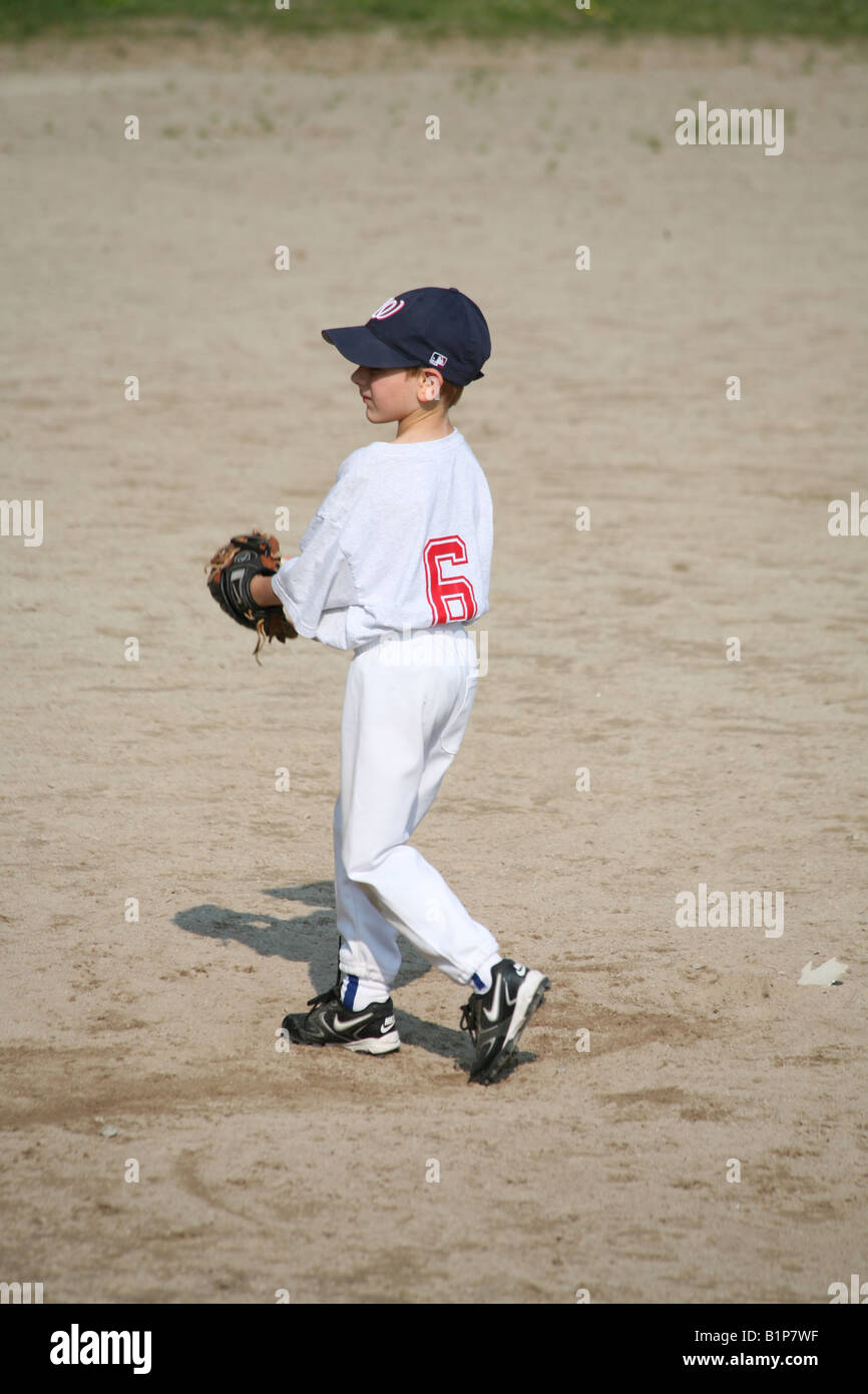 An eight year old boy is pitching at a Little League baseball game in