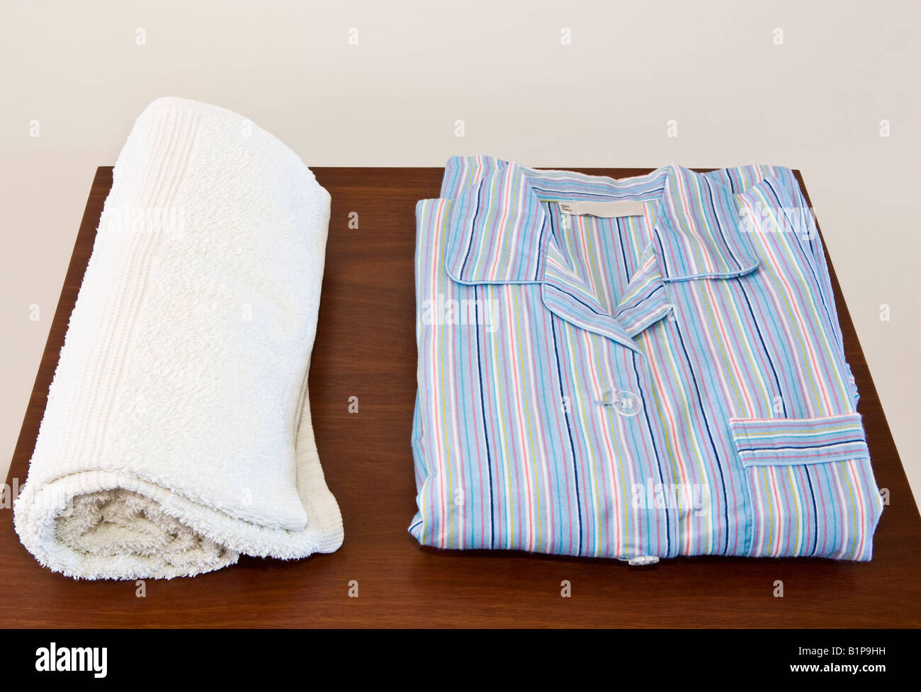 Pyjamas and a towel neatly set out on a bedside table Stock Photo