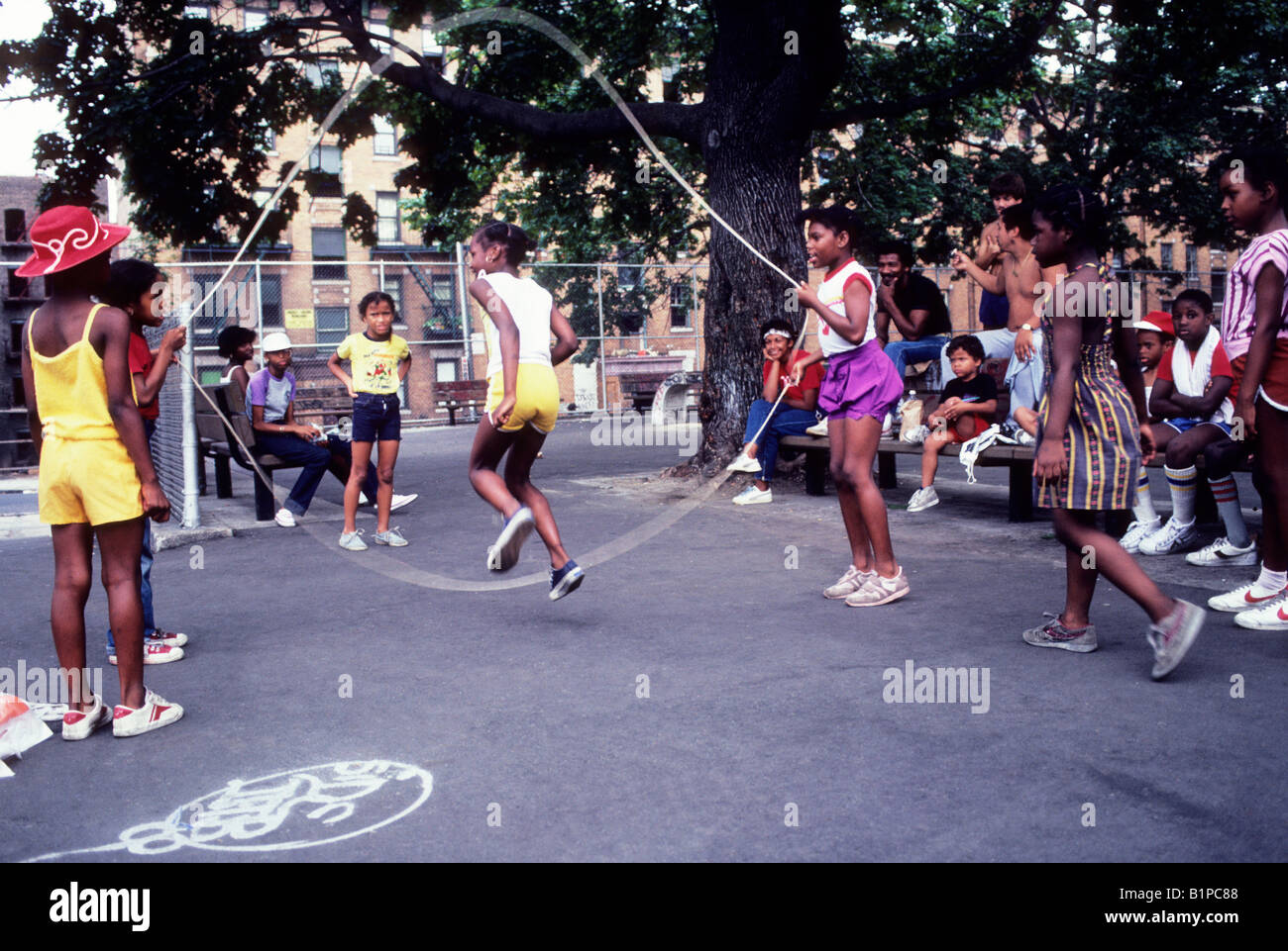 New York City the Bronx recreation time school playground Double Dutch girls jumping rope children of mixed ethnicity. Kids exercising. Competition. Stock Photo